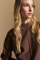 Polera de tejido de punto color marrón, con cuello alto y diseño de líneas verticales en el frente que aportan estructura. Presenta un calce relajado y mangas largas con puños ajustados.