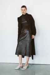 Trench fluido de corte recto confeccionado en lana, con cuello solapa, manga larga, bolsillos delanteros y cinturón ajustable del mismo tejido.