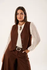 Chaleco marrón con escote en V, sin mangas y cierre frontal con botones.