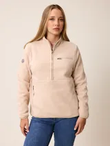Canguro de sherpa color beige, con cuello alto y medio cierre frontal. Presenta un bolsillo con cierre en el pecho y bolsillos laterales, confeccionado en tejido de textura suave.