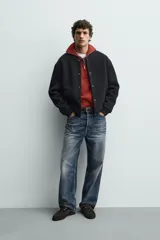 Chaqueta relaxed fit de color negro, confeccionada en tejido de canalé con mezcla de lana. Presenta cuello redondo, puños y dobladillo en rib elástico, bolsillos frontales de vivo y cierre con botones a presión.