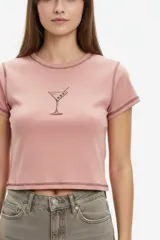 Remera cropped de algodón blanco, con cuello redondo y mangas cortas. Presenta costuras a contratono negras, dobladillos visibles y estampado de corazones en el pecho.
