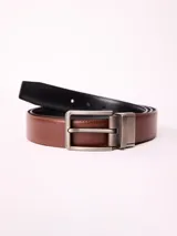 Cinturón reversible con una cara en color marrón y otra en color negro, confeccionado en cuero y poliuretano. Cuenta con una hebilla metálica de diseño clásico en acabado mate.