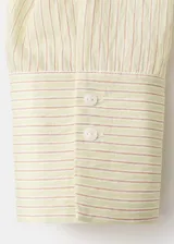 Camisa oversize color beige con sutiles rayas verticales, cuello camisero y cierre frontal con botones.