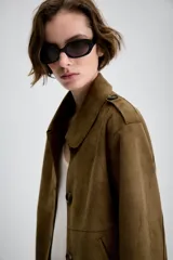 Chaqueta corta de efecto ante en color marrón, con cuello solapa, manga larga y trabillas en los hombros. Presenta cierre frontal con botones y bolsillos delanteros de doble vivo.