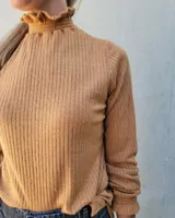 Polera de manga larga en tejido acanalado color blanco, con cuello alto y puños con detalle de punto smock fruncido.