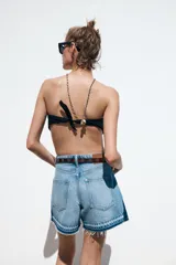 Shorts de jean de tiro medio, corte mom fit, con efecto lavado y terminación desflecada. Presenta cinco bolsillos y cierre frontal con cremallera y botón.