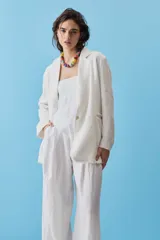 Blazer de lino color azul marino, de corte recto, con solapas y cierre frontal de un botón. Presenta detalles de flecos en los bordes.