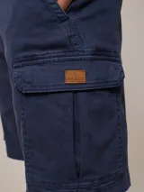 Bermuda cargo de sarga en color azul, con bolsillos laterales con solapa y cierre de botón. Diseño funcional con corte recto y ajuste cómodo.