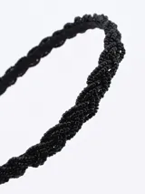 Vincha rígida color negro cubierta de cuentas negras.