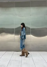Botas altas de gamuza color beige, con diseño slouchy, punta fina y una tira ancha superior con hebilla metálica rectangular y ojalillos.