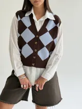 Chaleco tejido de punto con diseño de rombos en tonos marrón y celeste, con escote en V y cierre frontal con botones.