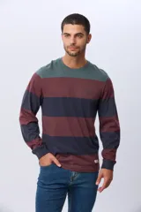 Remera de manga larga con diseño de rayas horizontales en tonos azul marino, beige y verde oscuro. Presenta cuello redondo y una pequeña estampa tipográfica en el pecho, además de una etiqueta decorativa en el ruedo.