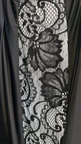 Vestido largo de fiesta color negro, con cuello halter alto y detalle de panel frontal de encaje transparente. Presenta diseño drapeado en el escote y la cintura, corte ajustado al cuerpo y espalda descubierta.