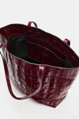 Bolso shopper de cuero bordó con estampado texturizado símil cocodrilo, diseño estructurado y doble asa fina para hombro.