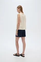 Musculosa de viscosa color beige claro, holgada, con cuello redondo y tirantes anchos formados por múltiples tiritas trenzadas.