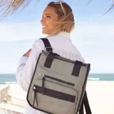 Mochila y cartera híbrida confeccionada en nylon de color beige con detalles y correas en negro. Posee dos asas superiores para llevar al hombro y correas traseras ajustables para usar como mochila. Presenta dos bolsillos frontales con cierre de cremallera y tiradores largos.