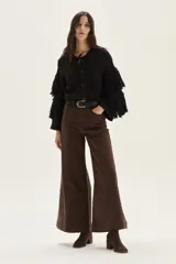Cardigan de tejido de punto con detalles calados, trenzas y flecos en mangas y espalda. Presenta cierre frontal con botones, cuello redondo y mangas tres cuartos.