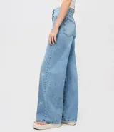 Pantalón de jean de algodón, modelo recto, con cintura mediana y trabillas. Presenta bolsillos delanteros y traseros, y un estampado localizado de flores de hibiscos.