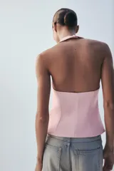 Top negro con estampado de lunares blancos, escote halter y diseño estructurado tipo corset con copas fruncidas en el centro.