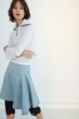 Falda midi de denim en tono azul claro, con tiro medio y diseño asimétrico con tablas laterales. Cuenta con cierre lateral mediante cremallera metálica.