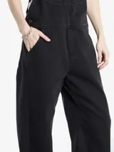 Enterito de jean Carhartt en color negro, con corte recto, tirantes ajustables y múltiples bolsillos frontales, incluyendo uno con el logo de la marca.