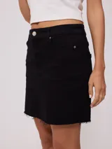 Falda de jean color negro, de corte recto y tiro medio, con ruedo deshilachado y cierre frontal con botón metálico.