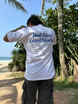 Remera blanca de algodón con estampa azul en la espalda con la frase "Bad Ideas Good Stories".