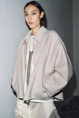 Chaqueta de lana en color beige, con cuello solapa, cierre frontal con cremallera metálica, mangas largas con corte evasé y bajo asimétrico.