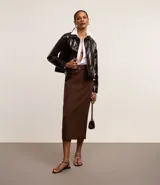 Pollera midi marrón de corte recto, con cinturón de hebilla redonda y detalle de encaje en la espalda.