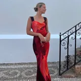 Vestido largo de satén con estampado abstracto en tonos cálidos como rojo, naranja y bordó. Presenta un escote drapeado, tirantes anchos y un corte entallado que se ajusta a la silueta.