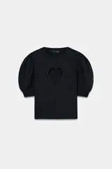 Jersey de punto negro con cuello redondo y mangas cortas abullonadas. Presenta una abertura frontal en forma de corazón.