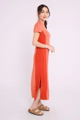 Vestido midi de corte recto y diseño bicolor, con frente en color crema y laterales en color beige. Presenta cuello redondo, mangas cortas y aberturas laterales en el ruedo.