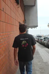 Remera negra de algodón 100% peinado, de corte recto y manga corta, con estampa estilo pixel art de cerezas y el texto "Cherry Season" en la espalda.
