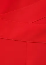 Mono largo rojo de tejido fluido con escote de pico, tirantes anchos, detalle cruzado en la cintura y cierre de cremallera invisible en la parte posterior.