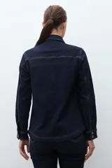 Camisa de jean de manga larga, color azul oscuro, con cuello camisero, botones frontales y bolsillos en el pecho.