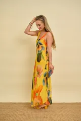 Vestido largo de gasa de seda con estampado floral en tonos amarillos, naranjas y verdes, sin mangas y corte al bies con caída fluida.