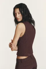 Chaleco de cuello solapa y manga sisa, color marrón con rayas verticales. Presenta cierre frontal con cremallera de doble cursor.