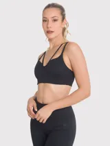 Top deportivo negro con diseño de tiras cruzadas en el frente, escote pronunciado y banda elástica inferior. Cuenta con almohadillas removibles y ofrece soporte medio.
