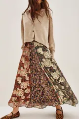 Falda larga plisada con diseño patchwork de diferentes estampados florales y abstractos en tonos otoñales y oscuros, con detalles metalizados. El forro es de poliéster.