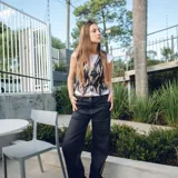 Chaleco corto con estampado abstracto en tonos dorados y azules, escote en V y cierre frontal con botones de madera.