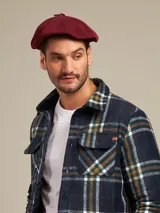 Boina azul marino de paño con visera pequeña y botón decorativo en la parte superior.