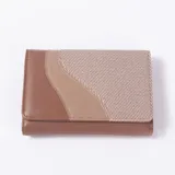 Billetera de cuero sintético y textil en tonos marrón, tostado y beige, con diseño de bloques curvos en la solapa y cierre de broche.