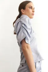 Blusa negra de seda con escote en V y mangas abullonadas cortas. Tiene cierre lateral.