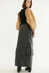 Falda midi de cuerina color marrón oscuro, corte recto, con bolsillos laterales y abertura frontal.