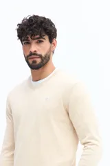 Sweater de punto color gris melange, con escote en V, manga larga y logo bordado en el pecho. Presenta puños y ruedo acanalados.