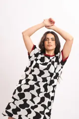 Vestido corto de tejido de punto con diseño abstracto en blanco y negro, mangas cortas y detalles en color rojo en el cuello y los puños.