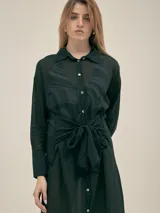 Vestido camisero largo negro con botones nacarados, lazo en la cintura y detalle de Polonio en cobre.
