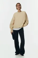 Buzo oversized de cuello redondo con hombros caídos, confeccionado con interior cepillado suave. Presenta puños y bajo en punto acanalado.