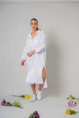 Túnica blanca estilo camisa, larga hasta la rodilla, con cuello clásico, abotonada al frente y aberturas laterales.